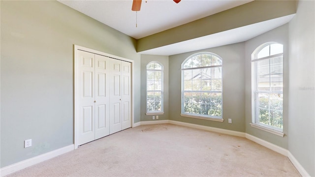 unfurnished bedroom featuring light carpet, a closet, and ceiling fan