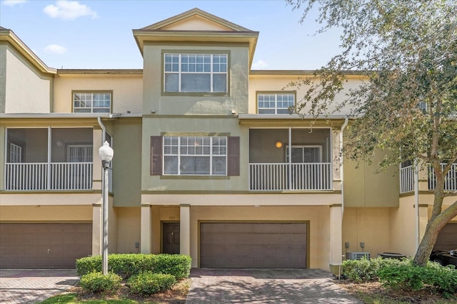 view of property featuring a garage, stucco siding, and decorative driveway
