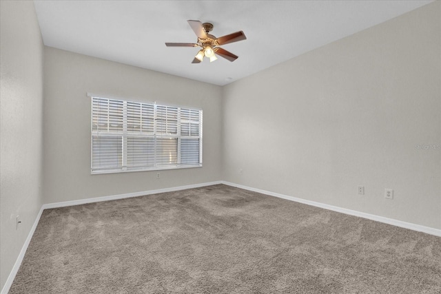 carpeted spare room featuring a ceiling fan and baseboards
