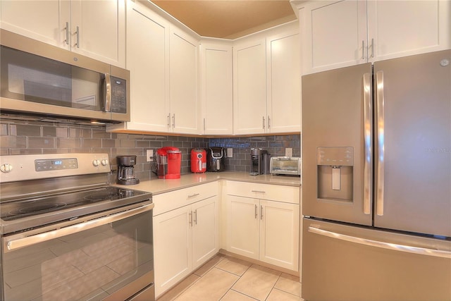 kitchen with white cabinets, appliances with stainless steel finishes, decorative backsplash, and light tile patterned flooring