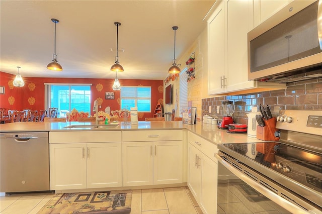 kitchen featuring decorative light fixtures, stainless steel appliances, light tile patterned floors, and sink