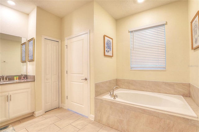 bathroom with tile patterned flooring, a textured ceiling, vanity, and tiled bath