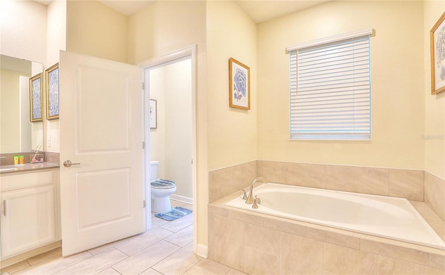 bathroom featuring tile patterned flooring, vanity, a relaxing tiled tub, and toilet