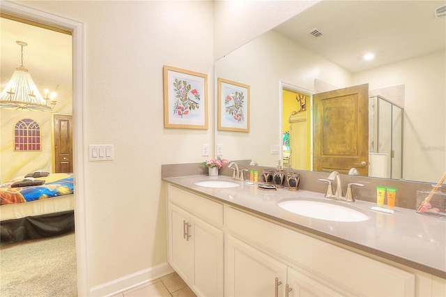 bathroom featuring tile patterned flooring, vanity, a shower with door, and an inviting chandelier