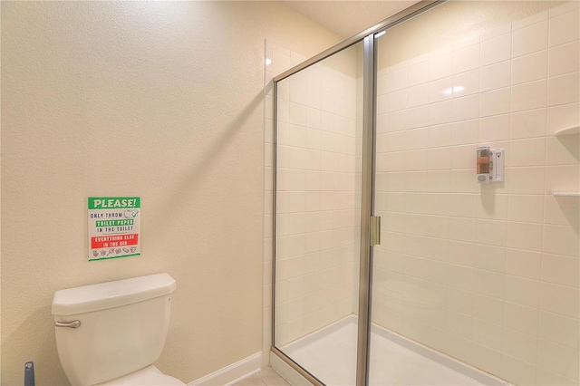 bathroom featuring toilet and a shower with door