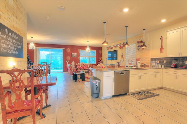 kitchen with kitchen peninsula, stainless steel dishwasher, sink, pendant lighting, and white cabinets