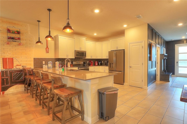 kitchen with hanging light fixtures, stainless steel appliances, kitchen peninsula, a breakfast bar area, and white cabinets