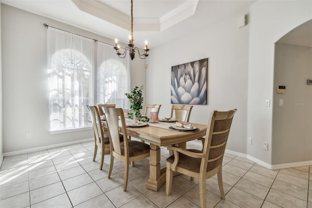 tiled dining space featuring crown molding, a tray ceiling, an inviting chandelier, and a wealth of natural light