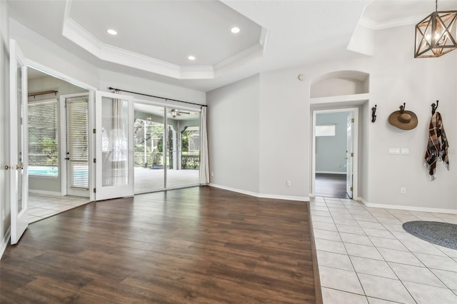 spare room featuring crown molding, a tray ceiling, light hardwood / wood-style flooring, and plenty of natural light