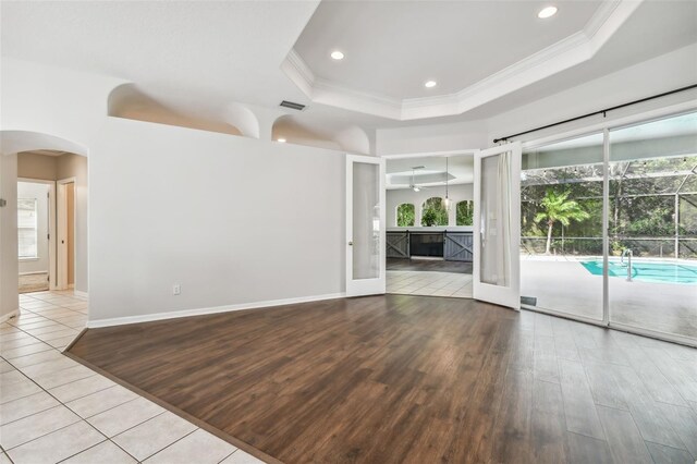 unfurnished living room featuring light hardwood / wood-style flooring, a raised ceiling, and crown molding