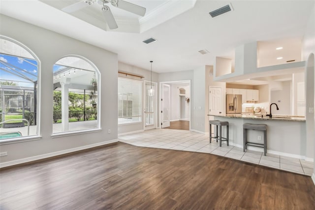 unfurnished living room with a tray ceiling, light hardwood / wood-style floors, and ceiling fan