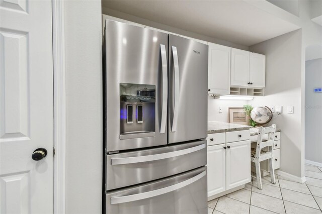 kitchen featuring stainless steel refrigerator with ice dispenser, light stone countertops, light tile patterned floors, and white cabinets