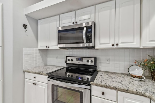 kitchen featuring white cabinetry, appliances with stainless steel finishes, light stone counters, and tasteful backsplash