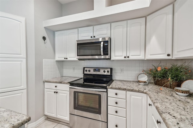 kitchen featuring light stone counters, stainless steel appliances, backsplash, and white cabinetry