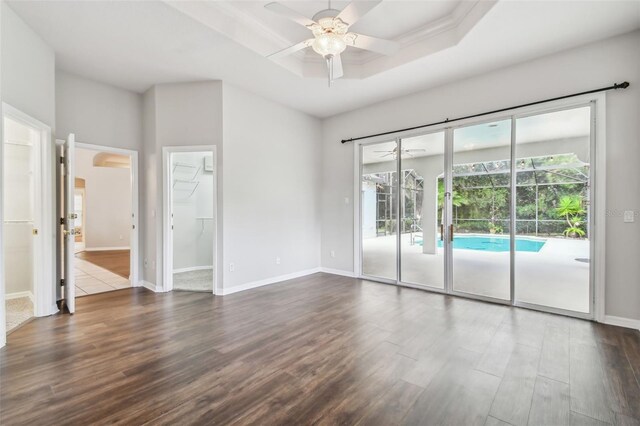 empty room featuring a tray ceiling, ceiling fan, and dark hardwood / wood-style flooring