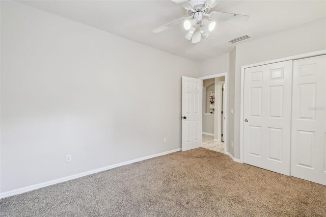 unfurnished bedroom featuring ceiling fan, light colored carpet, and a closet