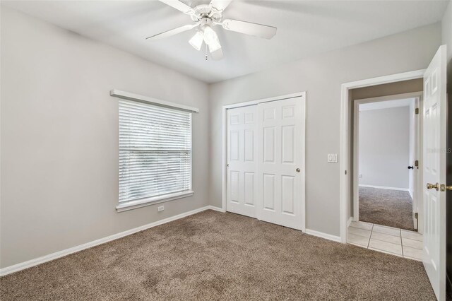 unfurnished bedroom featuring ceiling fan, light colored carpet, and a closet