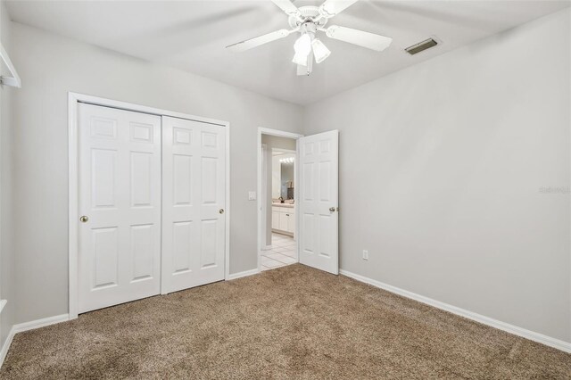 unfurnished bedroom featuring a closet, ceiling fan, and light colored carpet