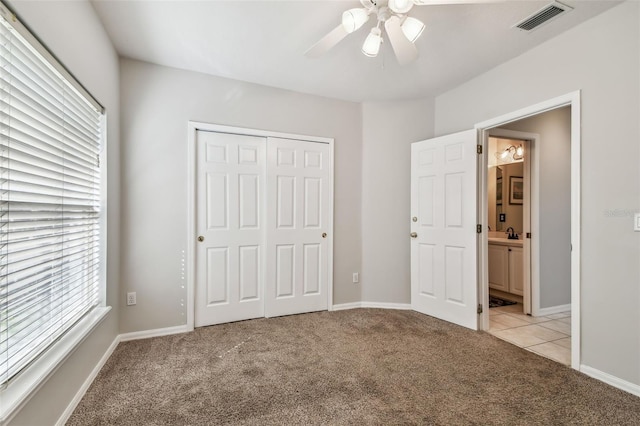 unfurnished bedroom featuring ceiling fan, light carpet, and a closet