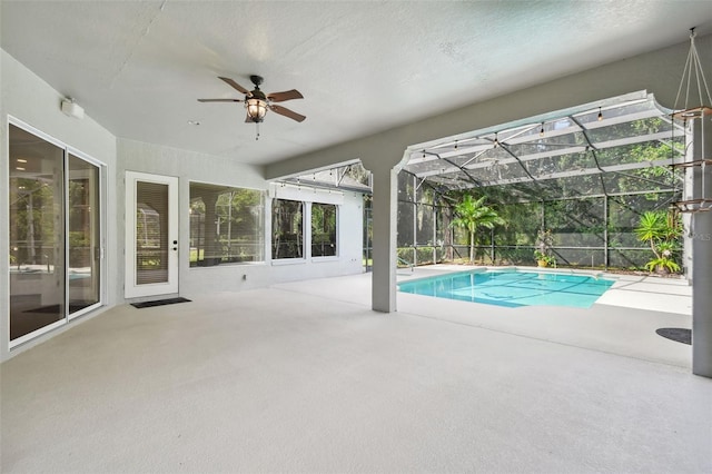 view of pool with glass enclosure, ceiling fan, and a patio area