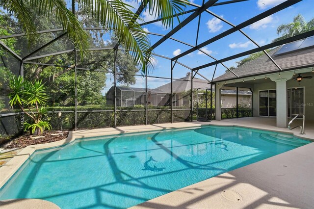 view of swimming pool with ceiling fan, a patio, and a lanai