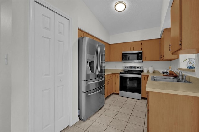 kitchen featuring sink, light tile patterned flooring, a textured ceiling, stainless steel appliances, and lofted ceiling