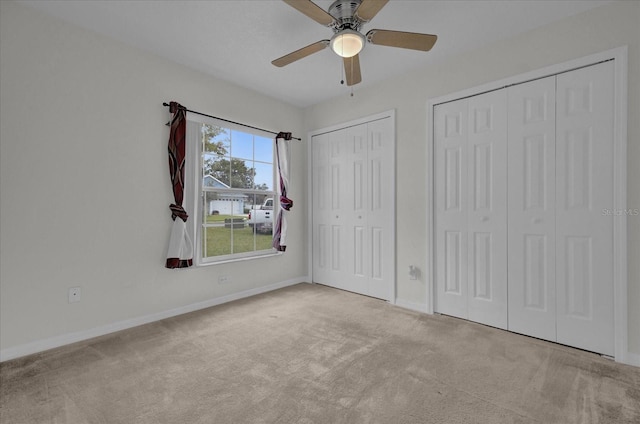 unfurnished bedroom featuring light carpet, two closets, and ceiling fan