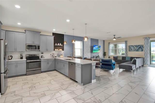 kitchen with ceiling fan, stainless steel appliances, kitchen peninsula, decorative light fixtures, and gray cabinets