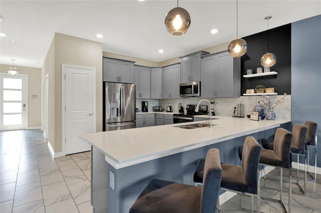 kitchen with a kitchen breakfast bar, sink, hanging light fixtures, and appliances with stainless steel finishes