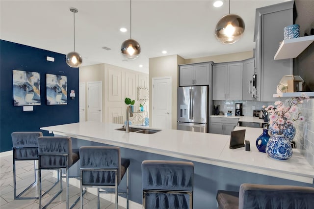 kitchen featuring appliances with stainless steel finishes, tasteful backsplash, gray cabinetry, sink, and hanging light fixtures