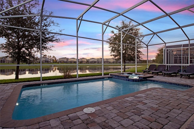 pool at dusk featuring an in ground hot tub, a patio, a water view, and a lanai