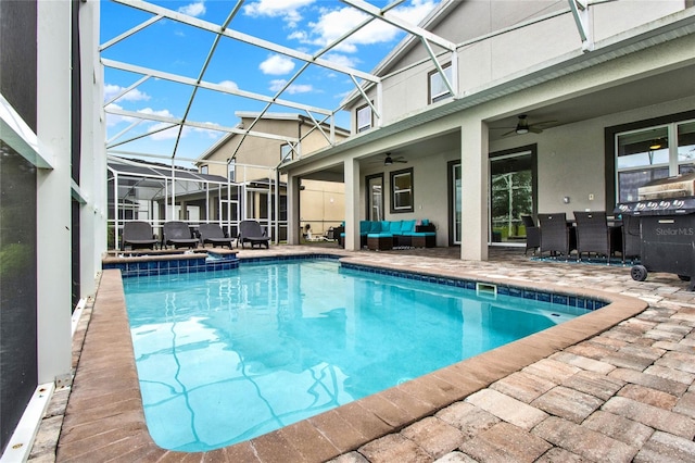 view of swimming pool with outdoor lounge area, a patio, glass enclosure, and ceiling fan