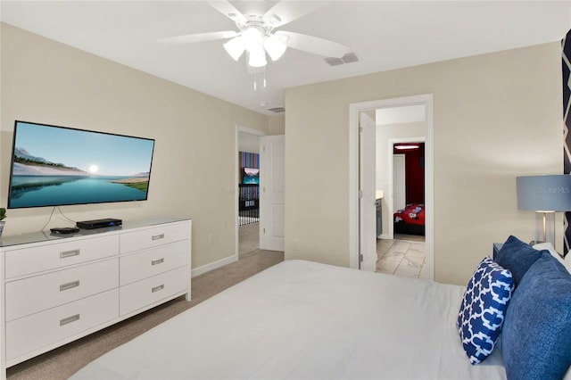 bedroom featuring light carpet, ensuite bathroom, and ceiling fan