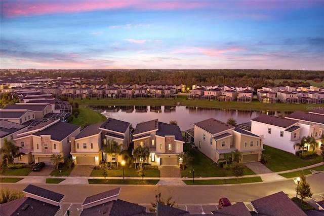 aerial view at dusk featuring a water view