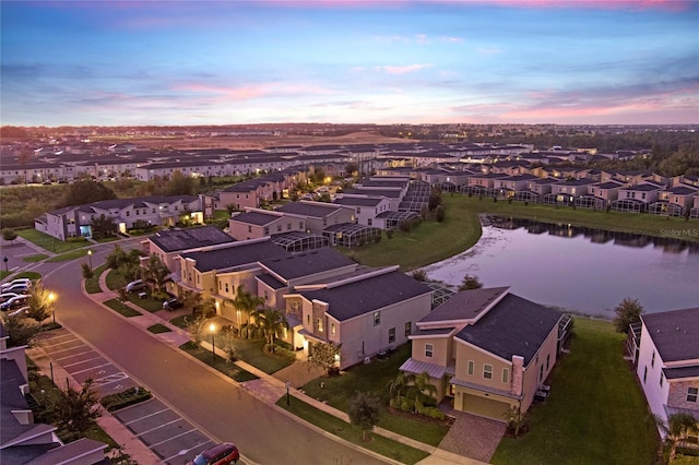 aerial view at dusk featuring a water view