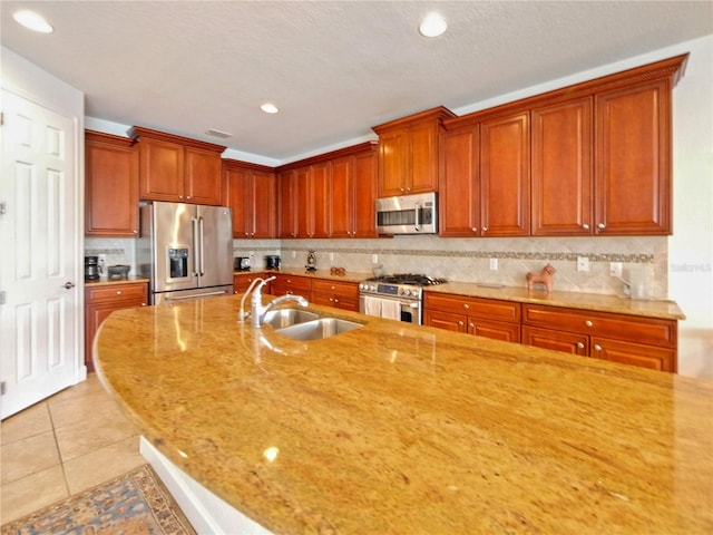 kitchen featuring light stone counters, sink, light tile patterned floors, tasteful backsplash, and stainless steel appliances