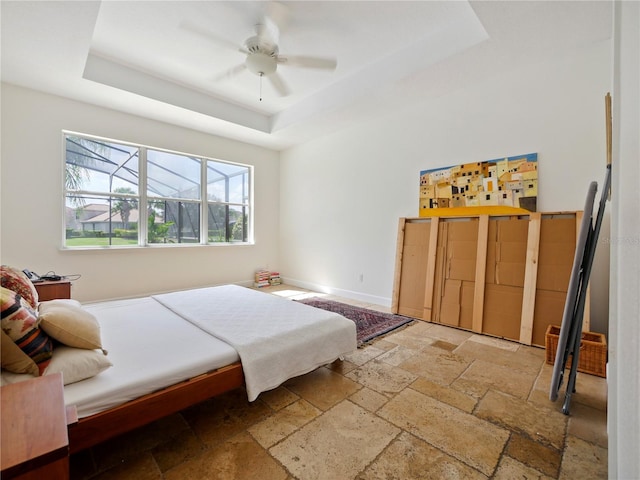 bedroom with ceiling fan and a raised ceiling