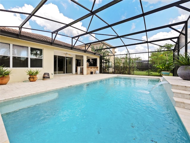 view of swimming pool with glass enclosure, ceiling fan, pool water feature, and a patio area