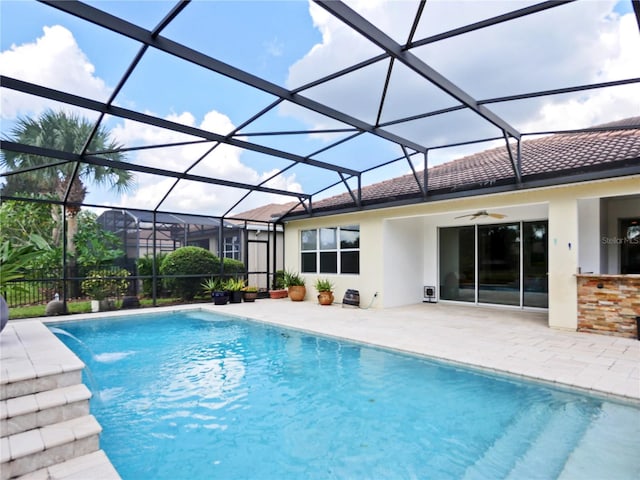 view of swimming pool featuring glass enclosure, ceiling fan, pool water feature, and a patio area