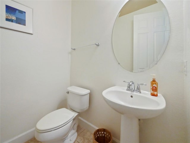 bathroom with toilet, sink, and tile patterned floors