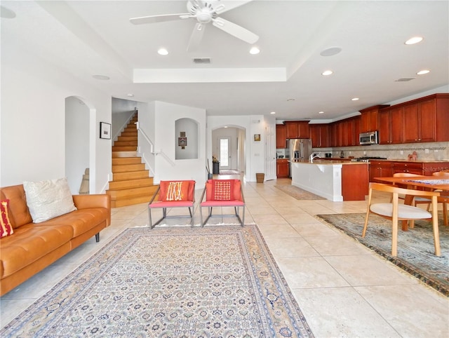 tiled living room with ceiling fan, a tray ceiling, and sink