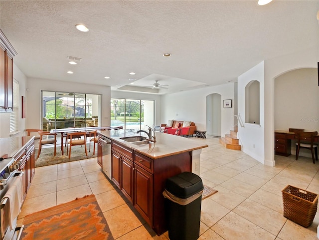 kitchen featuring sink, an island with sink, stainless steel appliances, light tile patterned floors, and ceiling fan