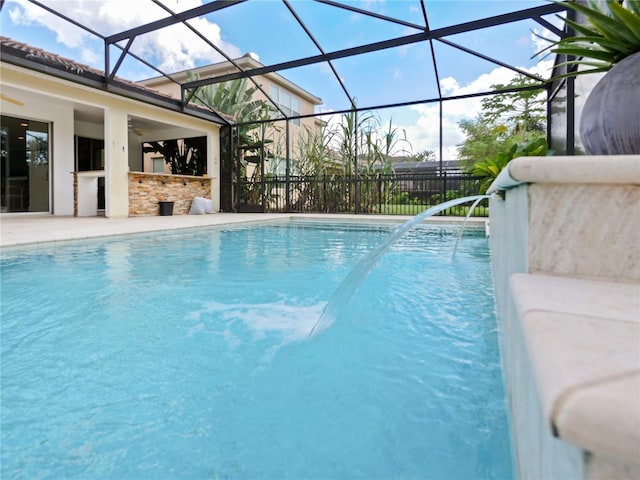 view of swimming pool featuring a patio, glass enclosure, and ceiling fan