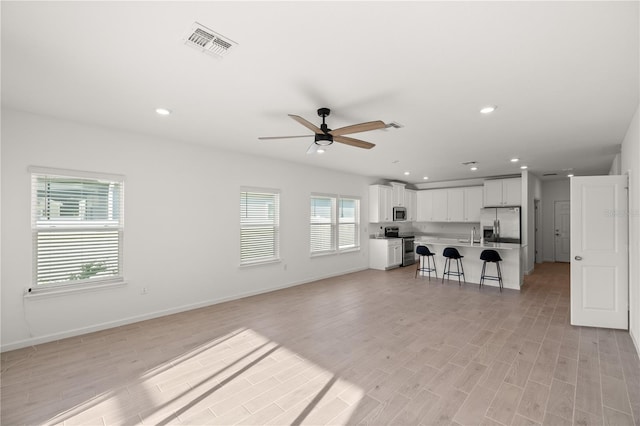 unfurnished living room featuring ceiling fan and light hardwood / wood-style floors