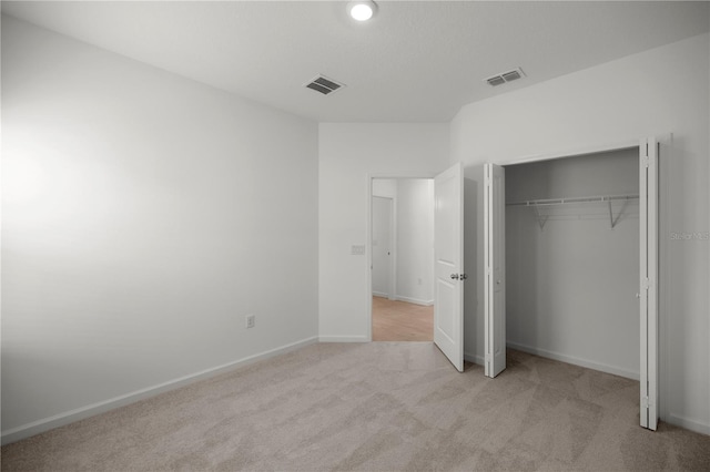 unfurnished bedroom with light colored carpet and a closet