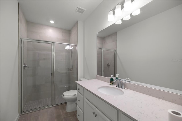 bathroom with hardwood / wood-style floors, a shower with shower door, vanity, and toilet