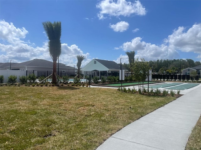 view of property's community featuring a yard, shuffleboard, and fence