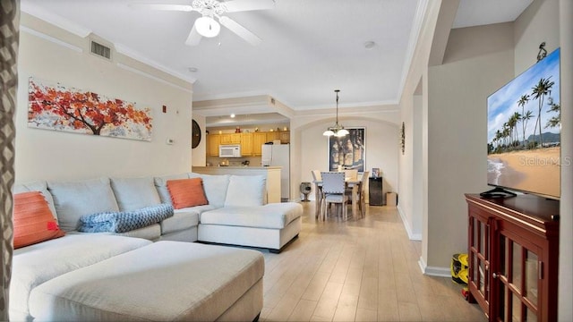 living room with light hardwood / wood-style floors, ornamental molding, and ceiling fan