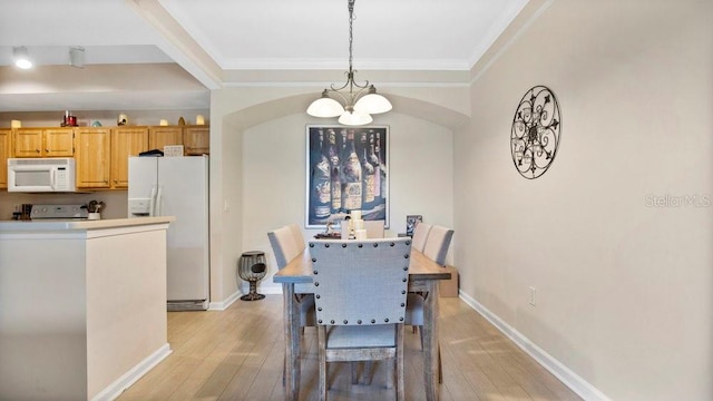 dining area with light hardwood / wood-style flooring, a chandelier, and crown molding