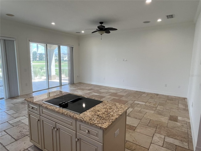 kitchen with black electric stovetop, a center island, ceiling fan, and light stone countertops